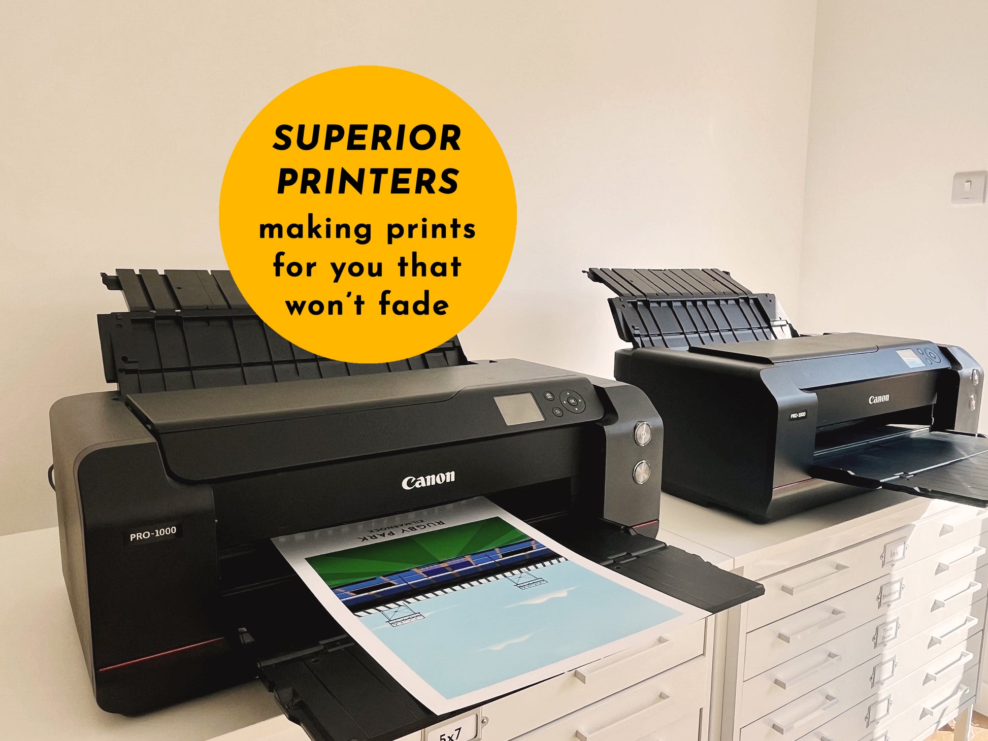 Canon printer with a printout on a desk, with another printer in the background.