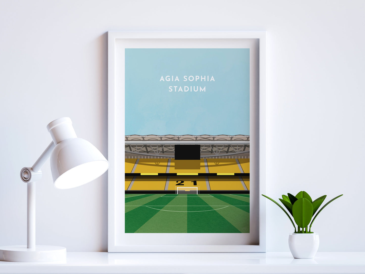 A contemporary style illustration of AEK Athens football stadium, the Agia Sophia Stadium, displayed as an art print within a white frame in a minimalist home office setting.