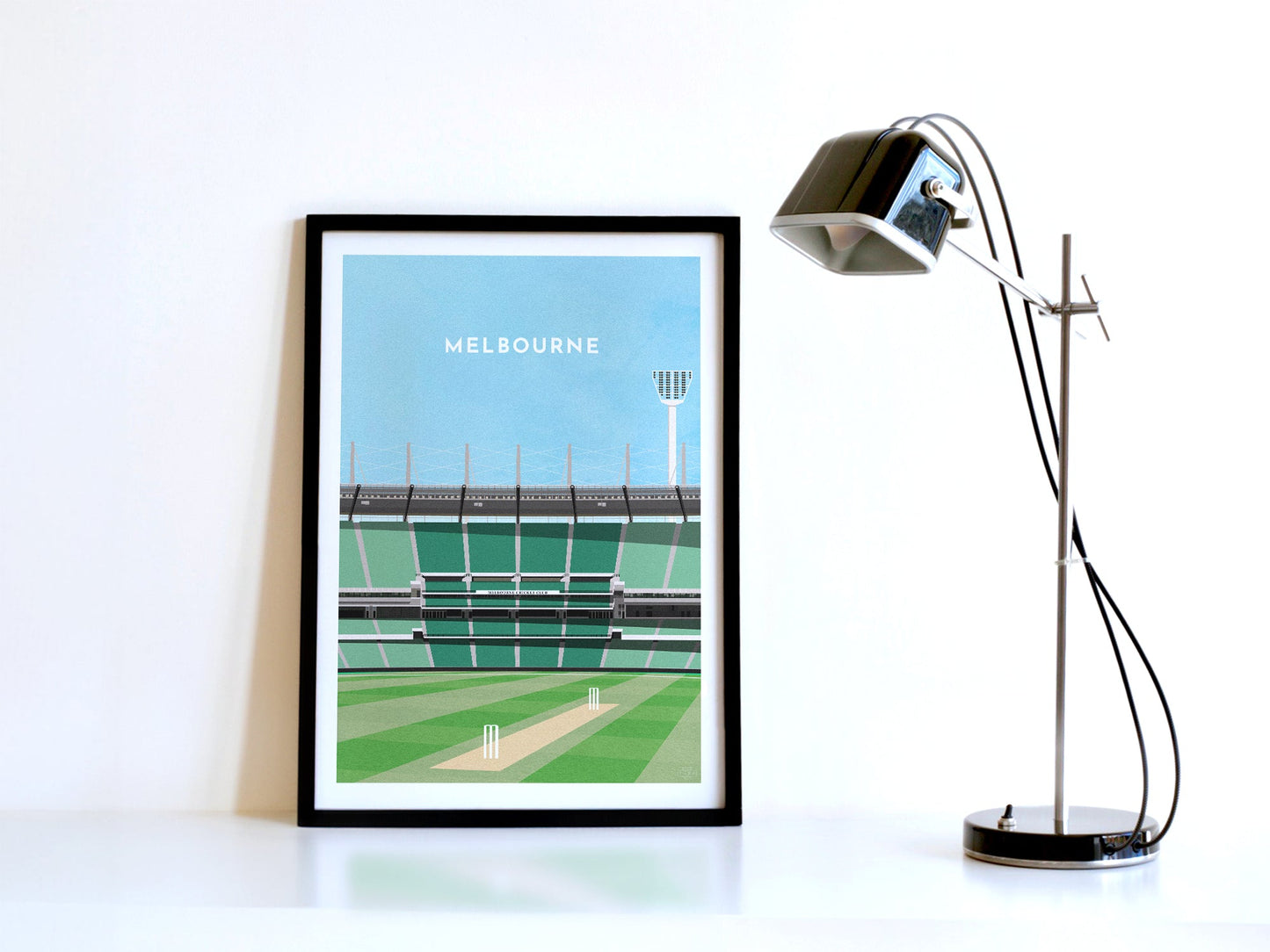 A contemporary style illustration of Australia and Melbourne's cricket stadium, the MCG, displayed as an art print within a black frame in a minimalist home office setting.