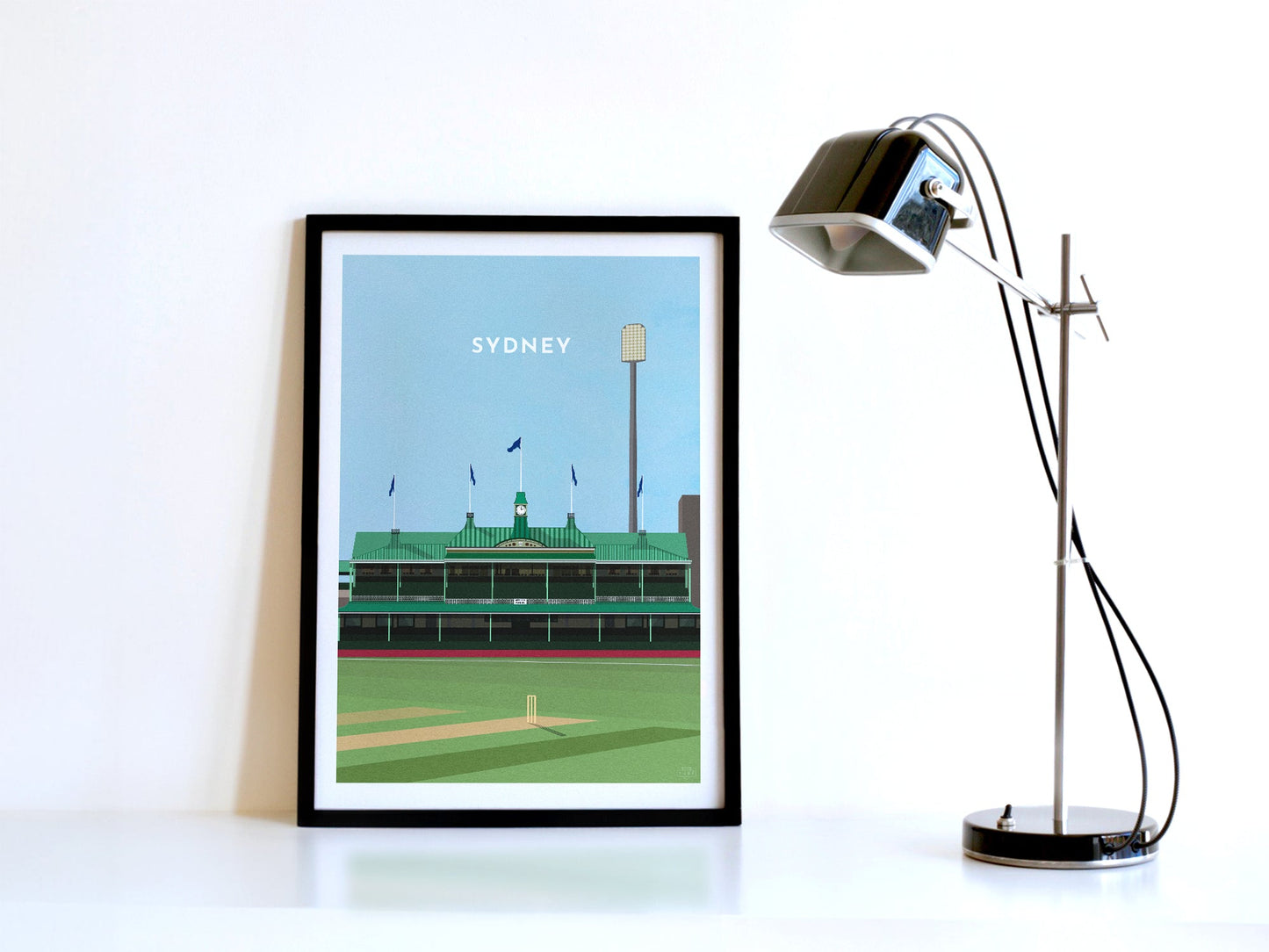 A contemporary style illustration of Australia and Sydney's Cricket Ground, the SCG, displayed as an art print within a black frame in a minimalist home office setting.