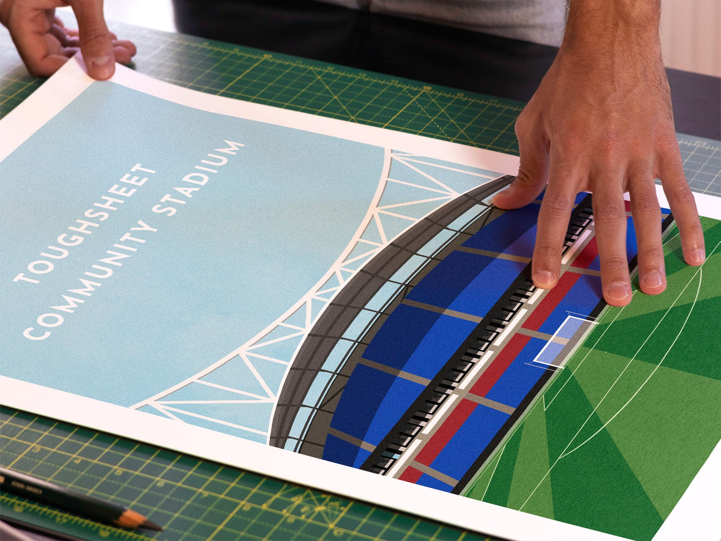 A photo in our printing studio, of one of our illustrated art prints of the Toughsheet Community Stadium after it has been printed and is about to be packaged.