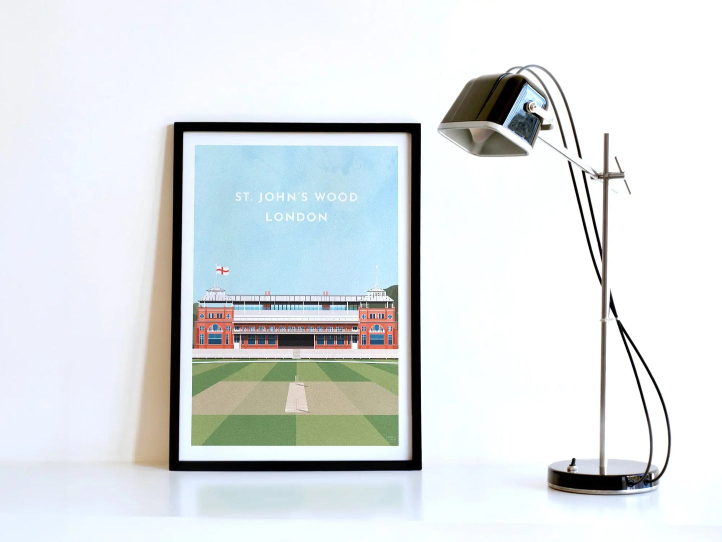 A contemporary style illustration of England cricket's ground, Lord's, displayed as an art print within a black frame in a minimalist home office setting.