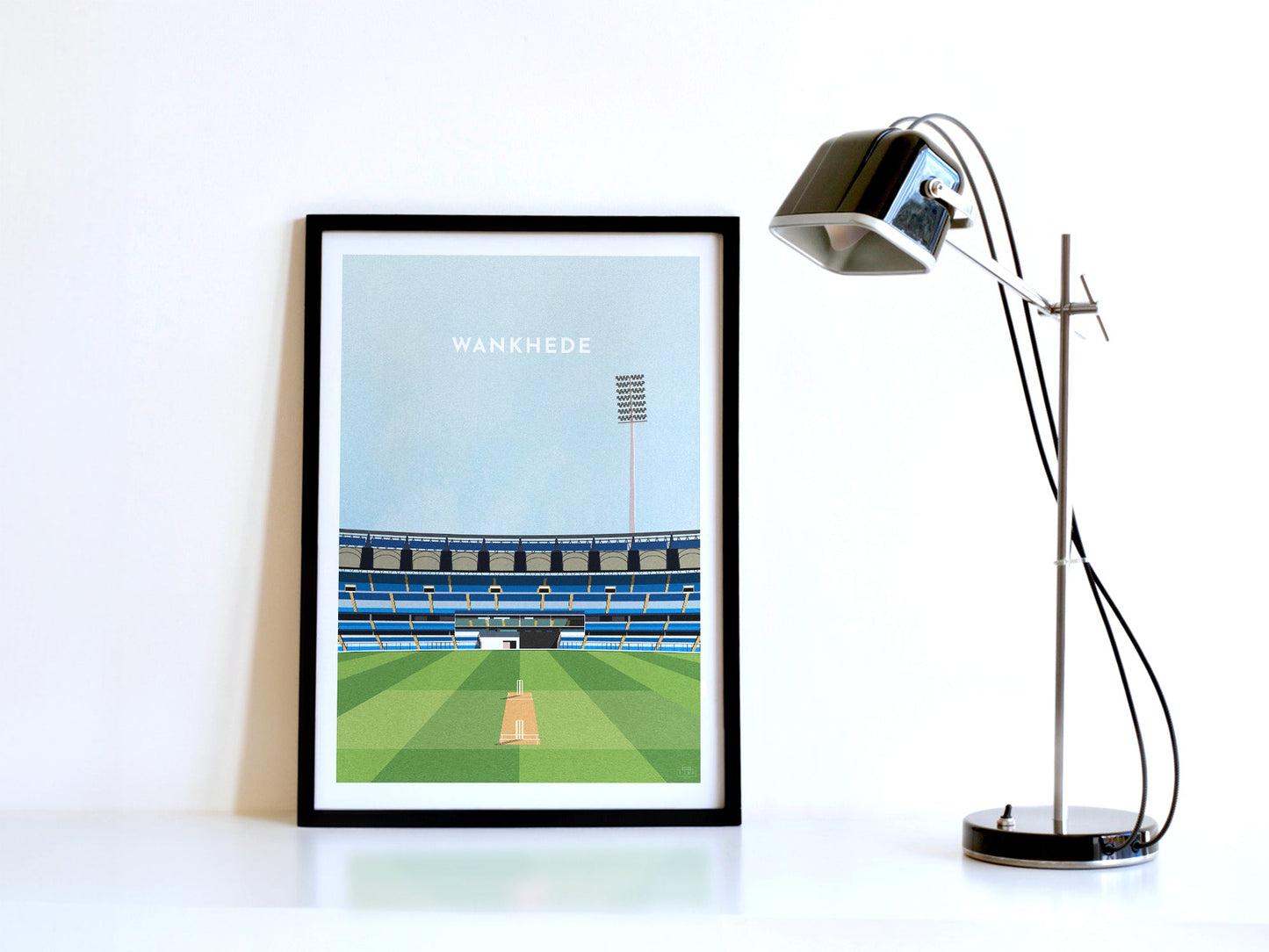 A contemporary style illustration of India and Mumbai's cricket stadium, Wankhede Stadium, displayed as an art print within a black frame in a minimalist home office setting.