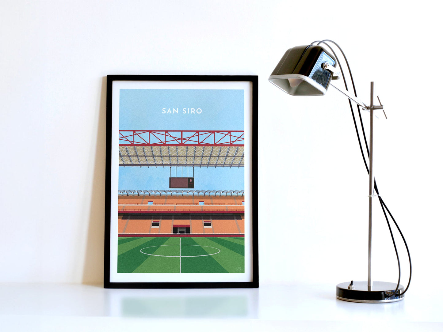 A contemporary style illustration of AC and Inter Milan's football stadium, the San Siro, displayed as an art print within a black frame in a minimalist home office setting.