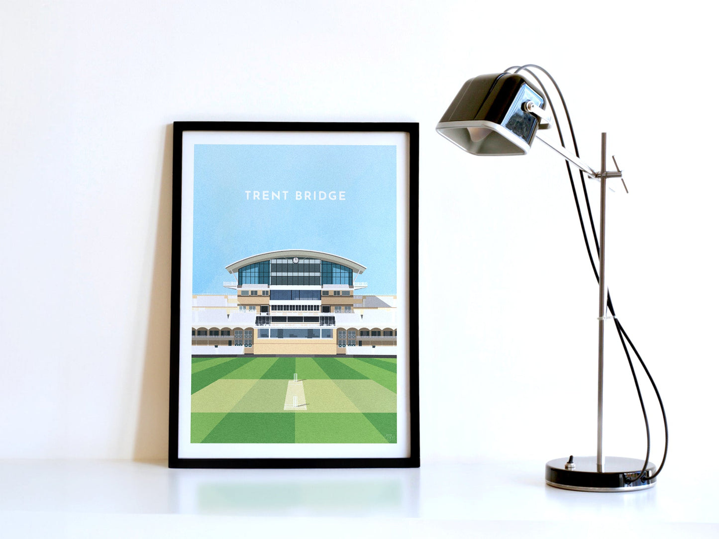 A contemporary style illustration of Nottinghamshire County Cricket's ground, Trent Bridge, displayed as an art print within a black frame in a minimalist home office setting.