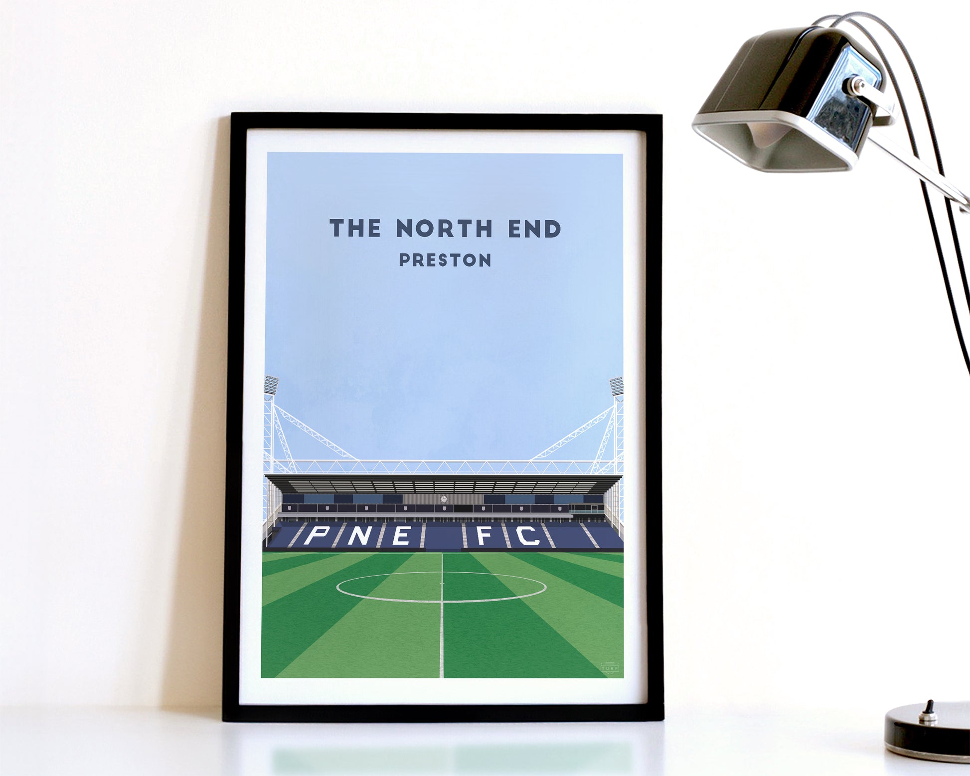 A modern style Preston North End Print, featuring a contemporary illustration of their home stadium the Deepdale Stadium in Preston, displayed within a black frame.