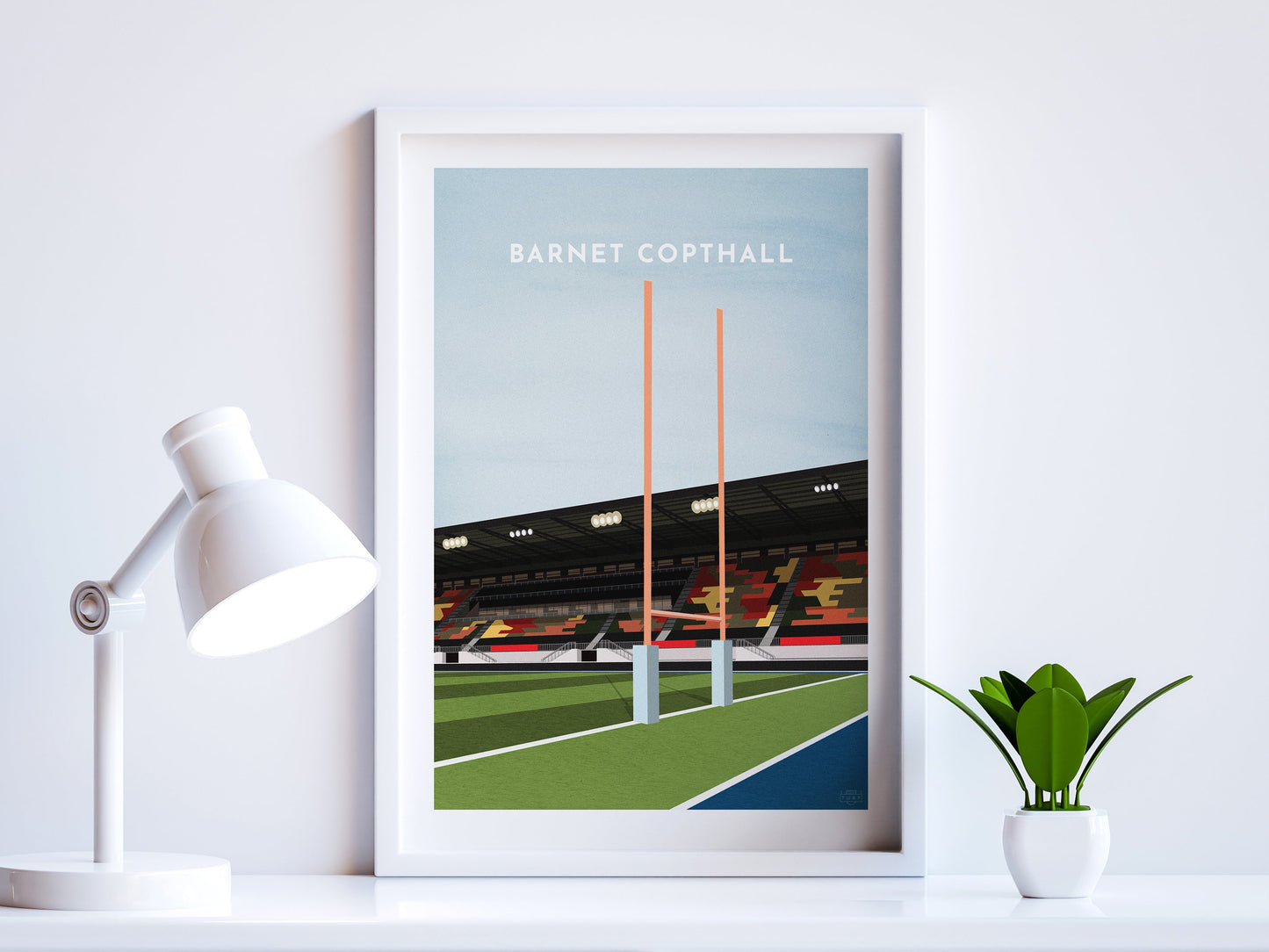 A contemporary style illustration of Saracens' Rugby stadium, the StoneX Stadium / Barnet Copthall, displayed as an art print within a white frame in a minimalist home office setting.