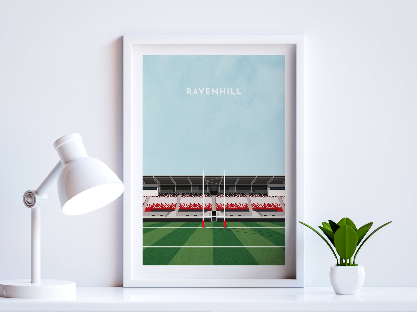 A contemporary style illustration of Ulster Rugby's rugby stadium, Ravenhill / Kingspan Stadium, displayed as an art print within a white frame in a minimalist home office setting.