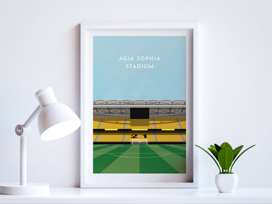 A contemporary style illustration of AEK Athens football stadium, the Agia Sophia Stadium, displayed as an art print within a white frame in a minimalist home office setting. 