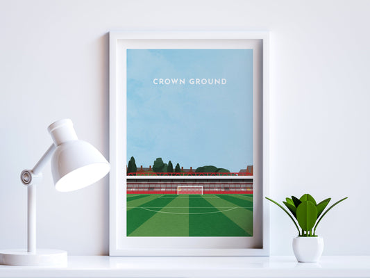 A contemporary style illustration of Accrington Stanley's football stadium, The Crown Ground / Wham Stadium, displayed as an art print within a white frame in a minimalist home office setting.