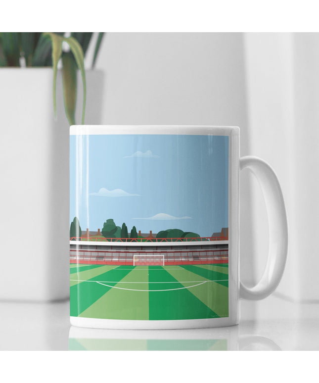 White Ceramic Mug with contemporary illustration of the Wham Stadium in Accrington, home to Accrington Stanley, showcasing a minimalist design with vibrant red stands, green football pitch, and the iconic stadium roof structure under a blue sky.