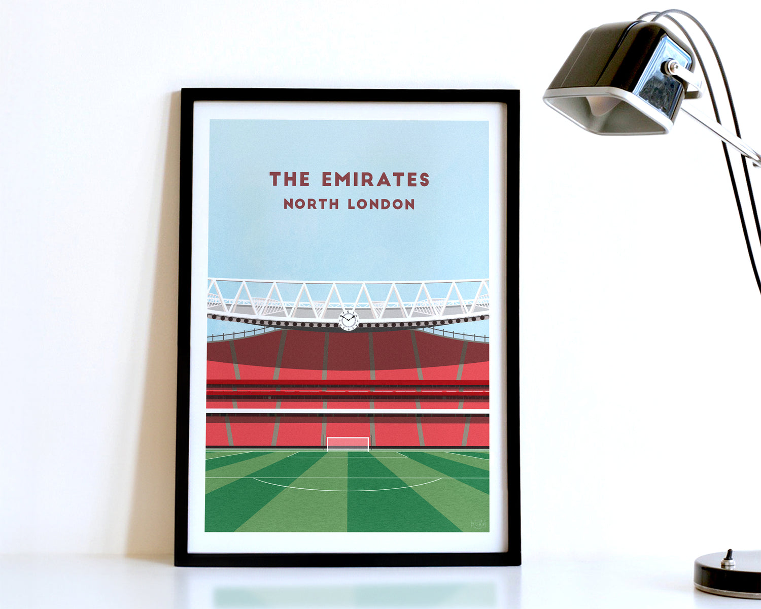 A modern style Arsenal Poster, featuring a contemporary illustration of their home stadium the Emirates Stadium in North London, displayed within a black frame.
