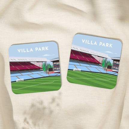 Two Square hardwood coasters laid on a tablecloth with glossy sublimation printed finish featuring contemporary illustration of Villa Park in Birmingham, home to Aston V, showcasing a minimalist design with vibrant claret & blue stands, green football pitch, under a blue sky.