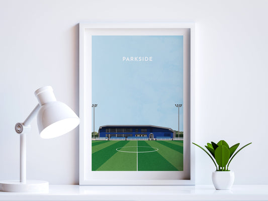 A contemporary style illustration of Aveley's football stadium, Parkside, displayed as an art print within a white frame in a minimalist home office setting. 