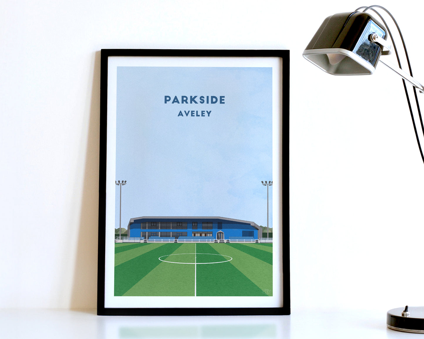 A modern style Aveley FC Poster, featuring a contemporary illustration of their home stadium the Parkside Stadium in Aveley, displayed within a black frame.