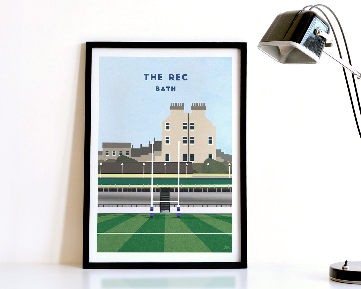 A modern style Bath Rugby Print, featuring a contemporary illustration of their home stadium The Rec in Bath, displayed within a black frame.
