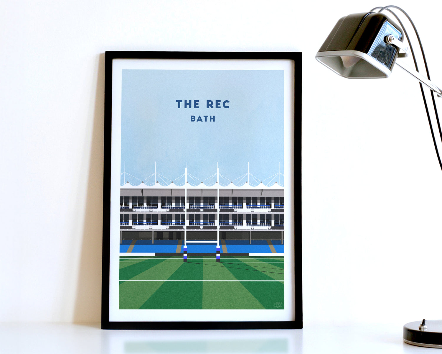 A modern style Bath Rugby Print, featuring a contemporary illustration of their home stadium the Recreation Ground in Bath, displayed within a black frame.