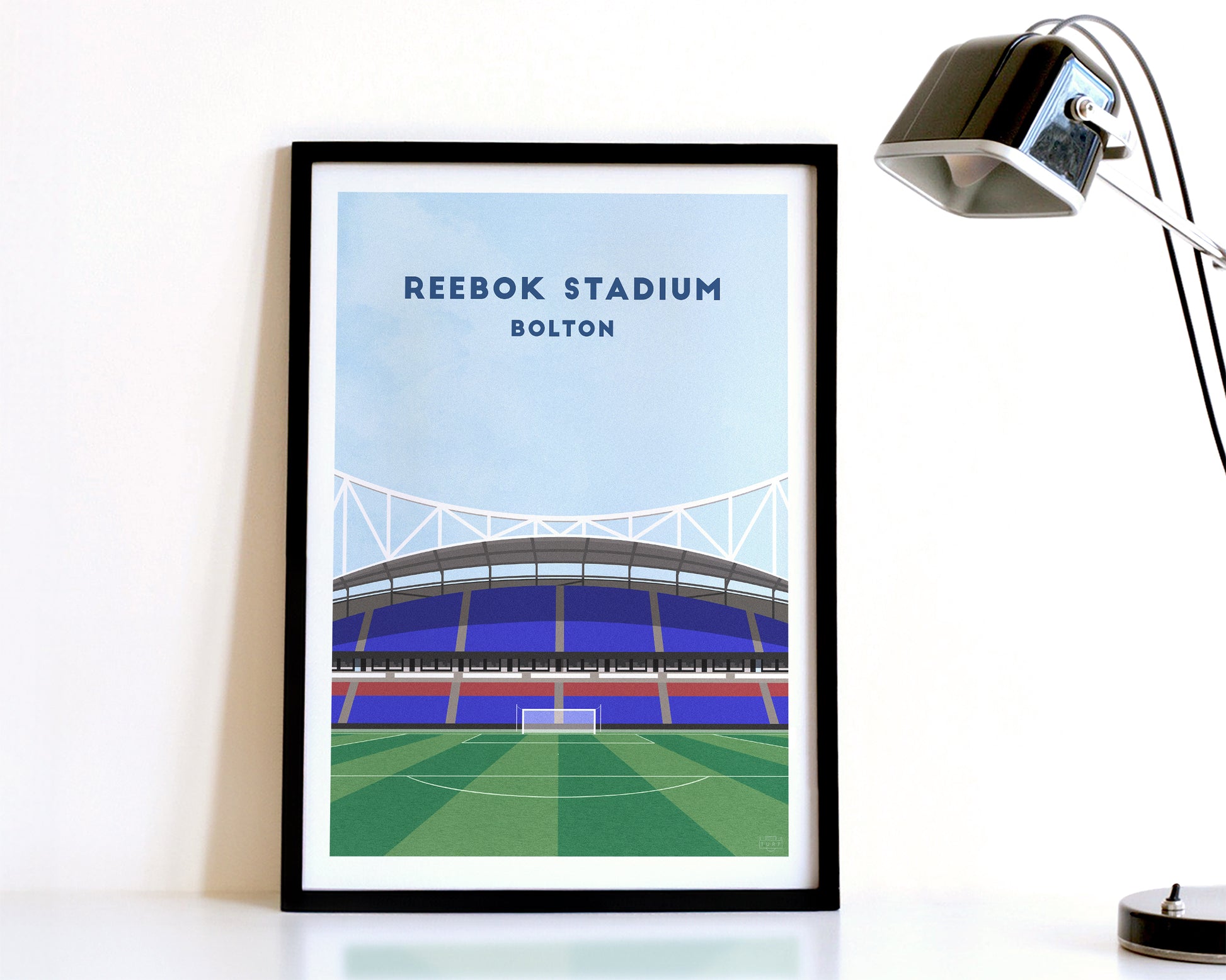 A modern style Bolton Wanderers Print, featuring a contemporary illustration of their home stadium the Reebok Stadium / Toughsheet Community Stadium in Bolton, displayed within a black frame.