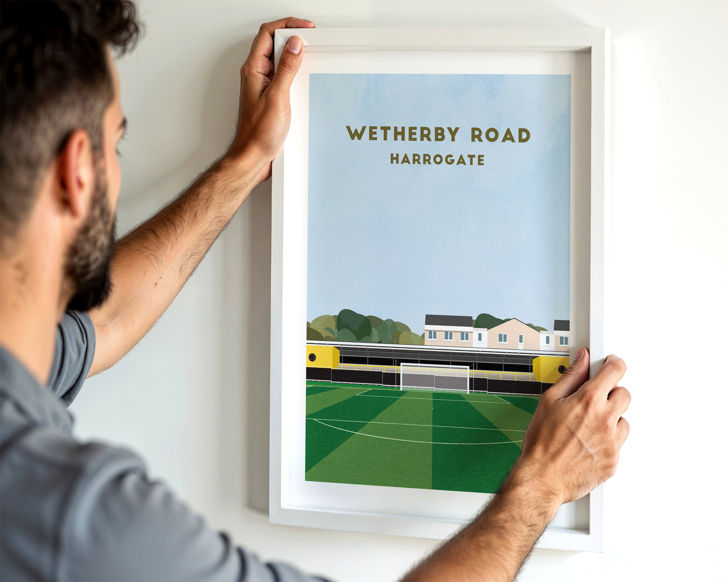 A modern style Harrogate Town Print, featuring a contemporary illustration of their home stadium the Wetherby Road in Harrogate, displayed within a black frame.