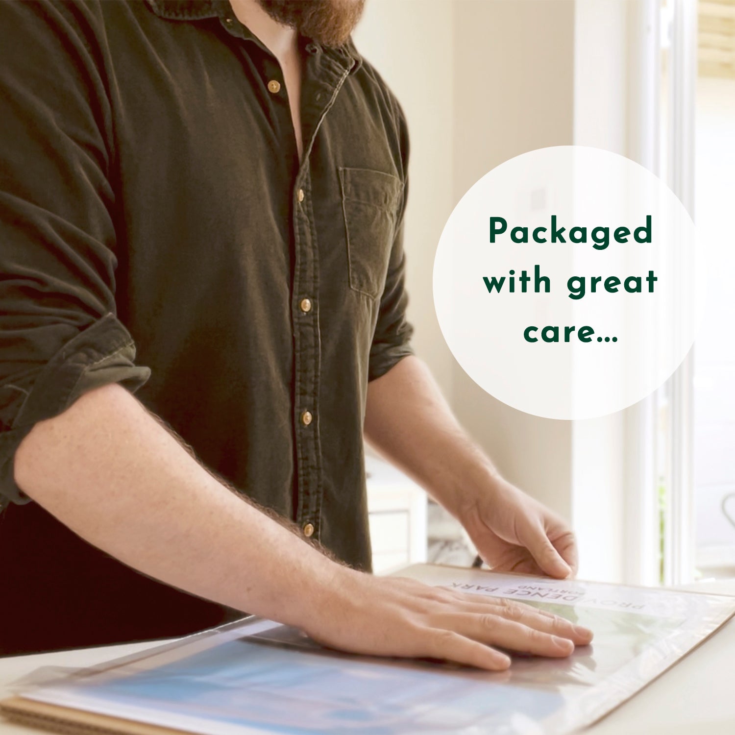 Photo of Ben carefully packaging up a customers print. Text overlay reads Packaged with great care...