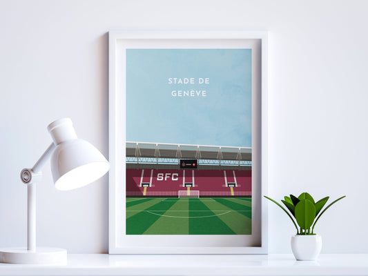 A contemporary style illustration of Servette's football stadium, Stade De Genève, displayed as an art print within a white frame in a minimalist home office setting. 